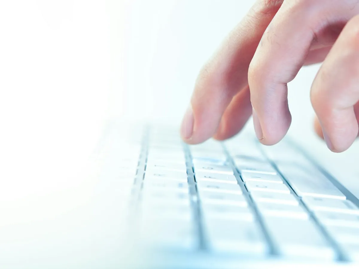 Doigts sur un clavier blanc, lumière froide