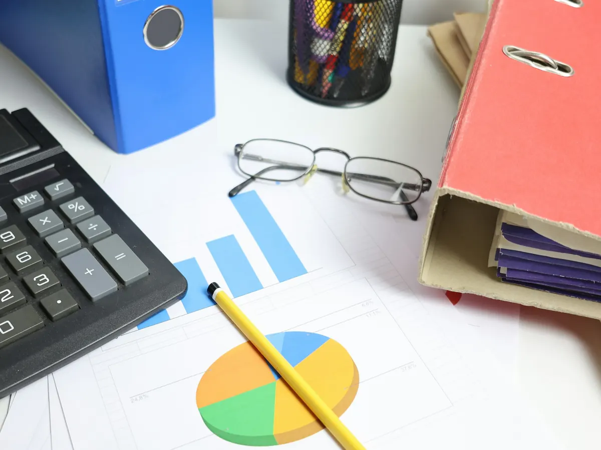 Bureau avec calculatrice, classeurs et tableaux imprimés
